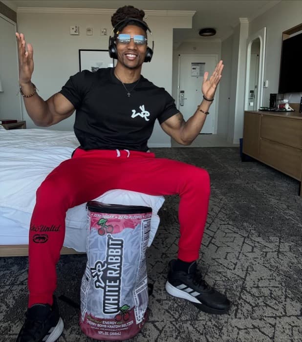 An athlete seated in a hotel room with a large White Rabbit Energy bag